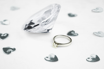 fake clear glass diamond  next to a wedding engagement ring