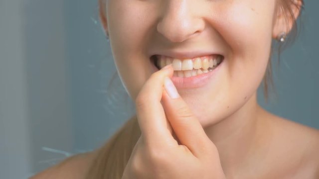 Closeup footage of young woman winkles out piece of food stuck in teeth