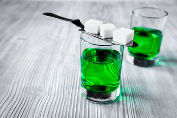 absinthe with sugar cubes and spoon on wooden background