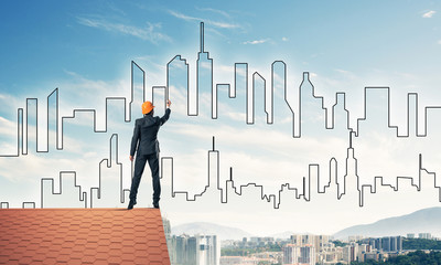 Man architect draw silhouette of modern city on blue sky. Mixed 