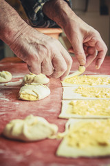 Old senior man hands rolling and wrapping pastry dough