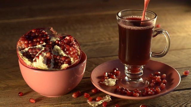 Pieces of the grenade in a Cup on a wooden table and poured juice in a glass with a stem.