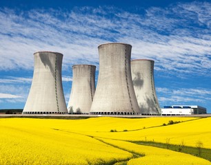 cooling tower with golden flowering field of rapeseed
