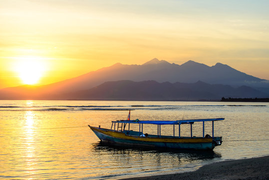 View over Lombok at sunrise with fisher boat in the front, Indonesia