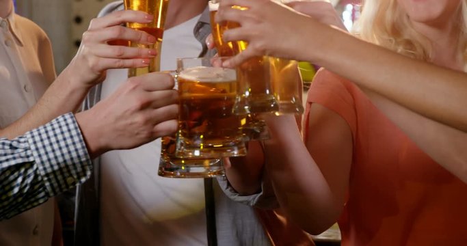 Friends toasting glasses of beer in bar 4k