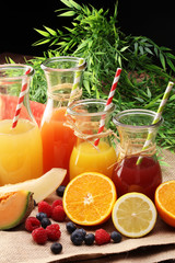 Apple and orange juice -several bottles with fruit and berry juices, vintage wooden background, selective focus