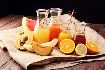 Apple and orange juice -several bottles with fruit and berry juices, vintage wooden background, selective focus