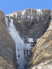 Fototapeta na wymiar frozen waterfall and ice stalactites on a rock face