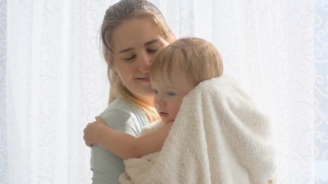 Beautiful caring mother hugging her baby son covered in blanket