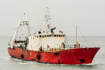 Red fishing boat sailing alone on the ocean near Mar del Plata,