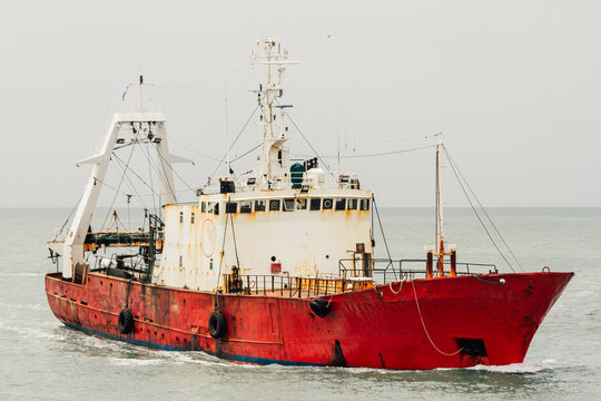 Red fishing boat sailing alone on the ocean near Mar del Plata,