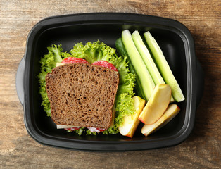 Lunch box with food on wooden background, top view