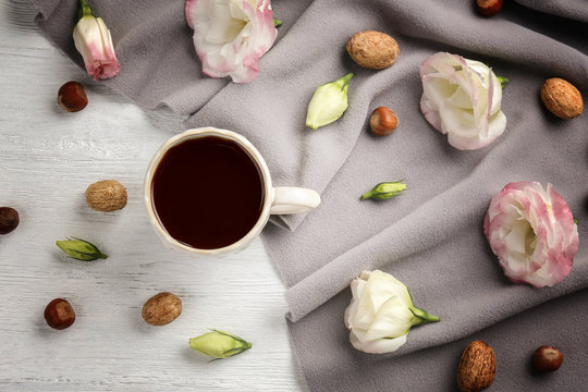 Beautiful composition with cup of coffee and flowers on white wooden background