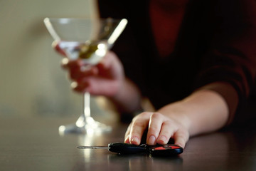 Woman with car key and glass of alcoholic beverage, closeup. Don't drink and drive concept