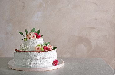 Delicious wedding cake on table and grey textured background