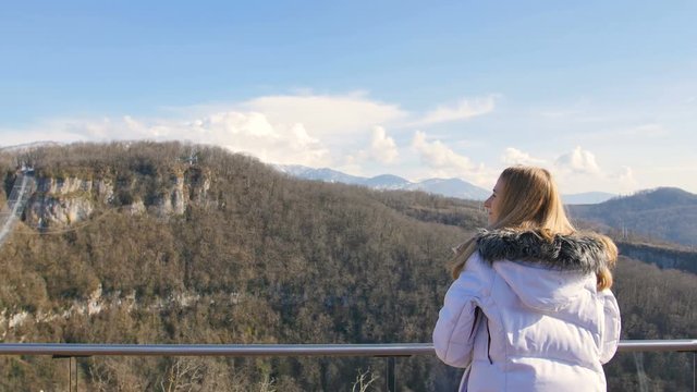 skybridge observation deck. Woman enjoing sunlight and scenery view of the mountains