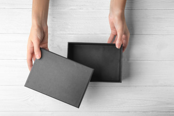 Female hands opening black box, on wooden background