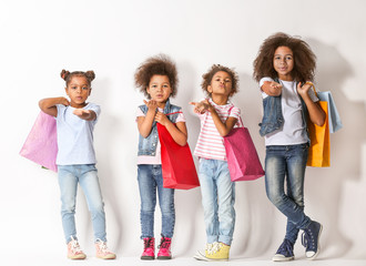 Fototapeta premium Four cute African girls with shopping bags on white background