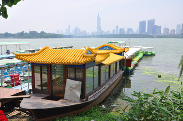 Tourism Boat at Xuanwu Lake with Nanjing skyline and Zifeng Tower at the background in Nanjing, Jiangsu Province, China.