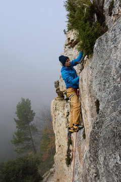 Rock climber ascending a challenging cliff. Extreme sport climbing. Freedom, risk, challenge, success.