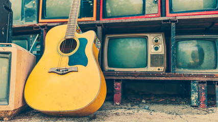 Classic guitar laying down on retro television in vintage style.
