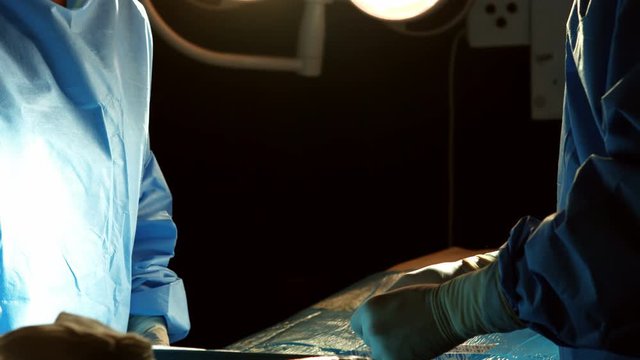 Mid section of surgeons performing operation in operation room at the hospital 4k