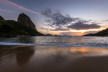 Beautiful Sunrise in the Beach with Few Clouds in the Sky, Sugarloaf Mountain in the Horizon, and Reflection of Sun in the Sand, Rio de Janeiro, Brazil