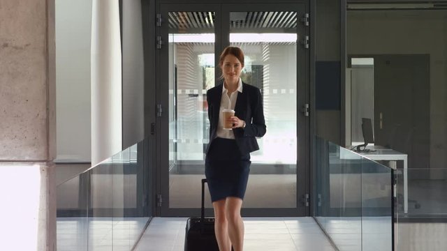 Businesswoman walking with luggage in office