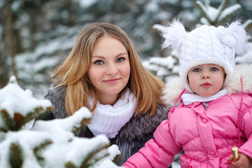 Fototapeta premium Mother holds daughter on hands outdoors frost. Family portrait. Family walk in a winter park. Family happiness.