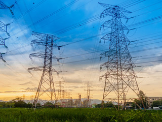 Twilight photo of High voltage post or High voltage tower in green field and power plant at Butterworth, Penang, Malaysia