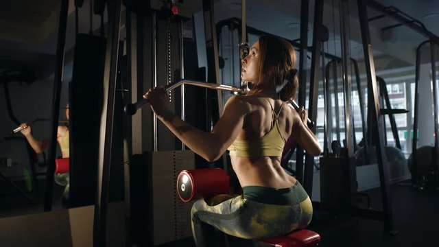 Young woman doing exercise for back on training machine