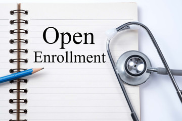 Stethoscope on notebook and pencil with Open Enrollment words as