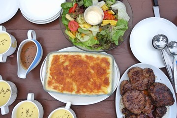 Top view of dining table with steak salad potato gratin and soup Family meal time