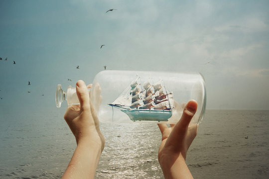 Textured image of a child holding a ship in a bottle at the ocea