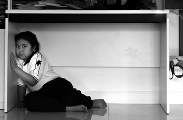 Sad upset unhappy boy kid hiding under the table.