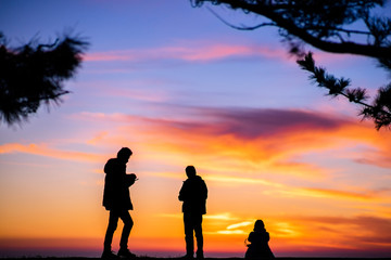 Silhouette of People are looking down the phone to light Twilight sea.