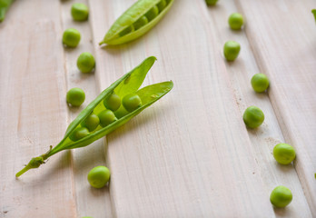 Split, green pea pod and peas on wooden background close up