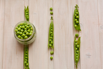 Top view of fresh, sweet, split pea pods and pea seeds in glass plate on wooden background