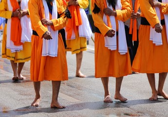 men of Sikh Religion with long orange clothes walk barefoot with