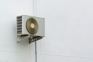 Air conditioner compressor unit on white wall.