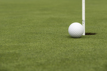 Golf ball close to pin and hole
