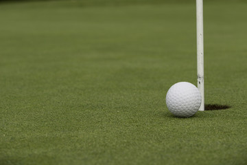 Golf ball close to pin and hole