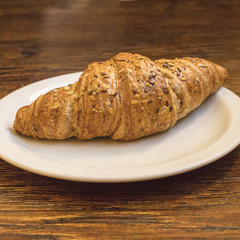 Cereal croissant on wooden table with copy space