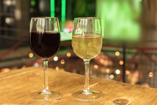 Red and white wine glasses on blurred lights background