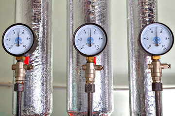 Three pressure gauge in boiler room, next to heat conductor.