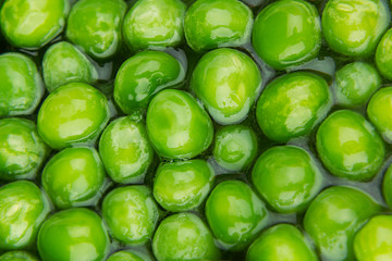 Wet fresh green peas in water closeup as background. Healthy vitamin food.
