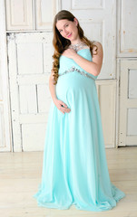 Young smiling beautiful pregnant woman in blue loose dress