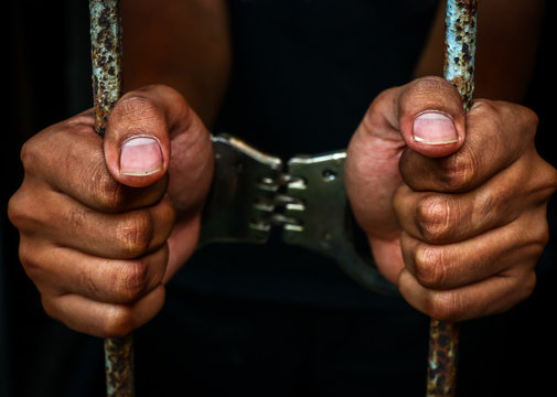 Human hand of prisoner on steel lattice close up.