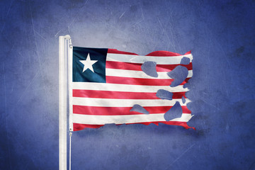Torn flag of Liberia flying against grunge background