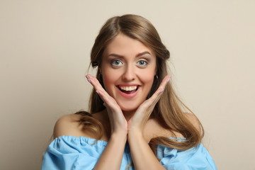 Cheerful girl with long wavy hair holds her face.